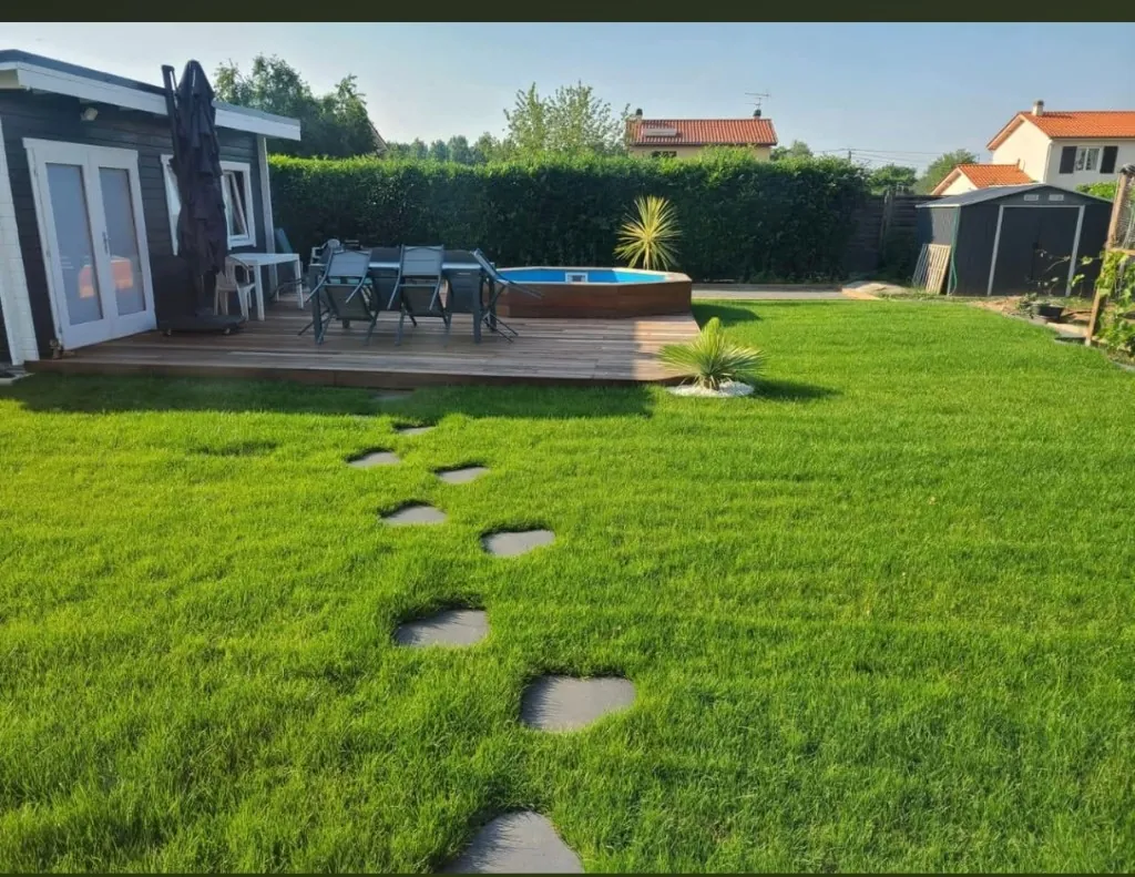 Jardin engazonné avec plage de piscine en bois après travaux