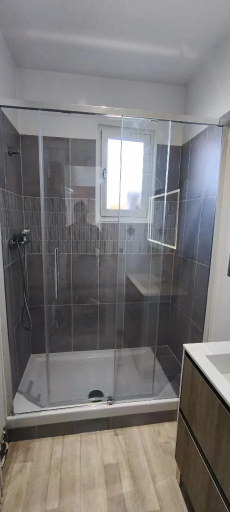 Salle de bain terminée : douche, paroi vitrée et robinetterie